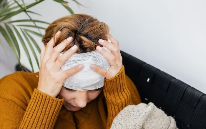 woman holding her bandaged head