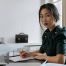 woman sitting at desk with pen in front of various documents